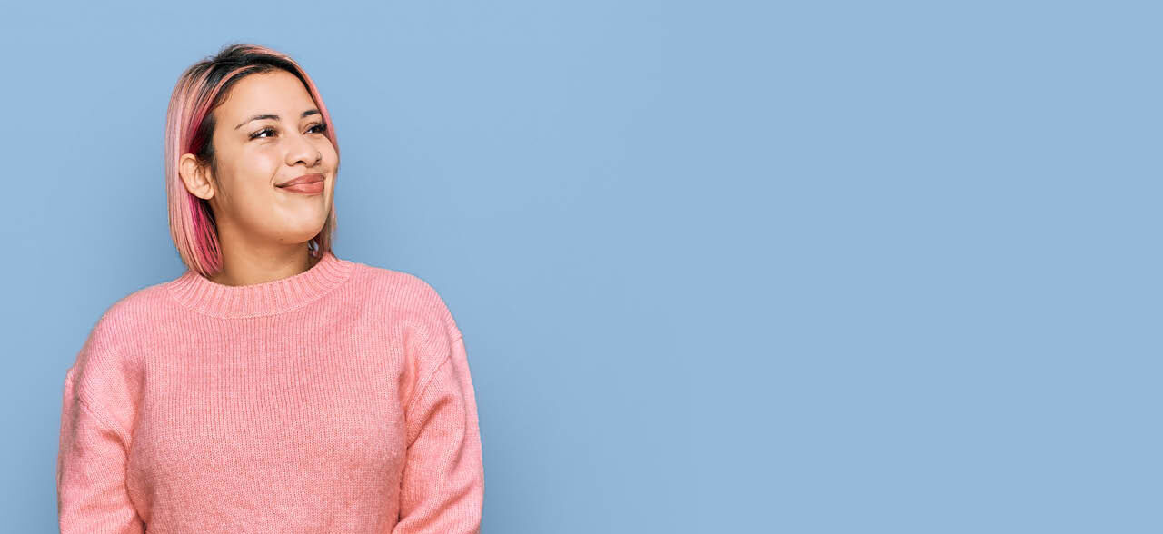 eine lächelnde Frau mit rosa Haaren und einem rosa Pullover
